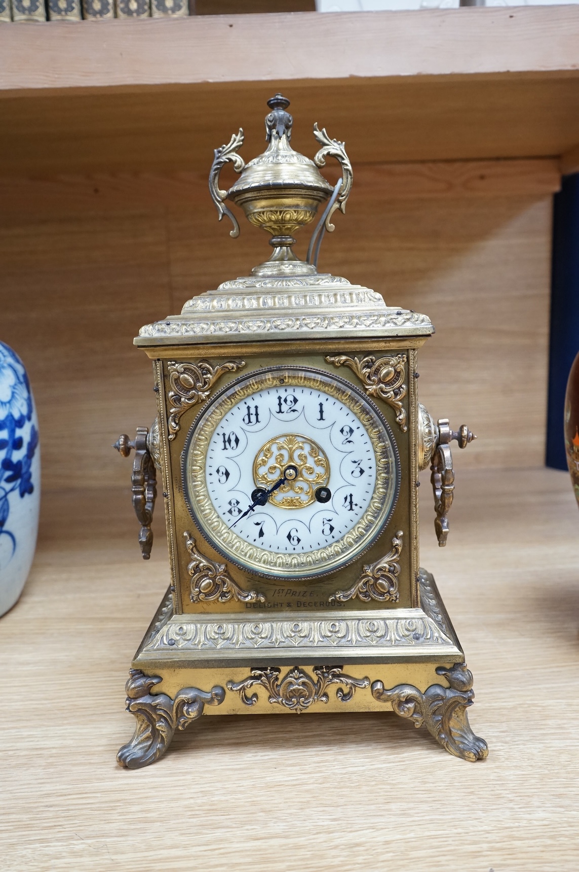 A decorative brass mantel clock with urn surmount, with 1st prize engraved panel, 41cm high